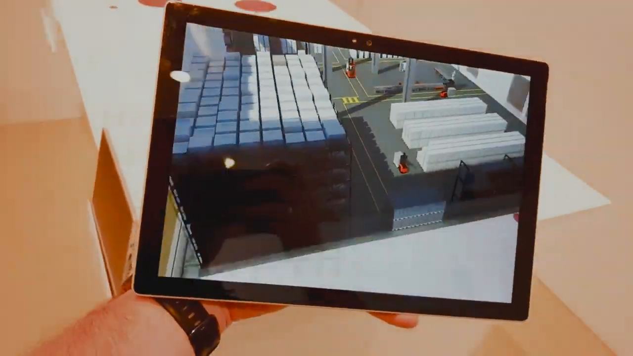 A tablet in a hand showing the warehouse in augmented reality